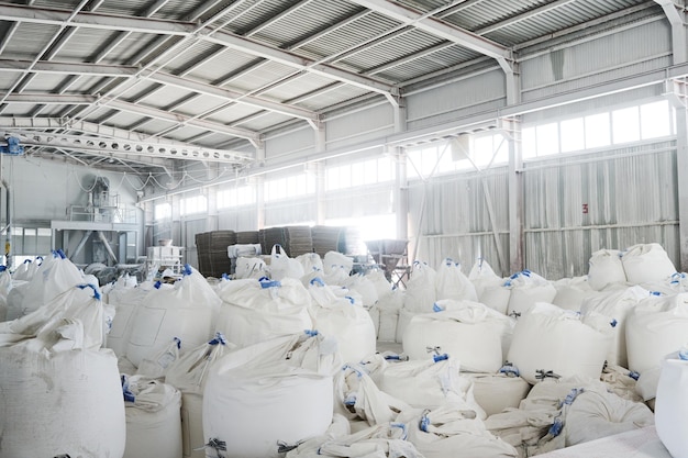 Part of spacious warehouse or storage room with heaps of huge white sacks