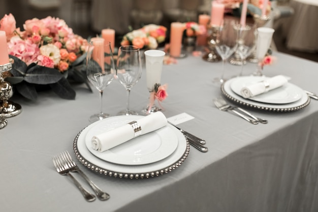 Part of stylish table setting with plate and cutlery. Nearby lies a white business card. Copy space