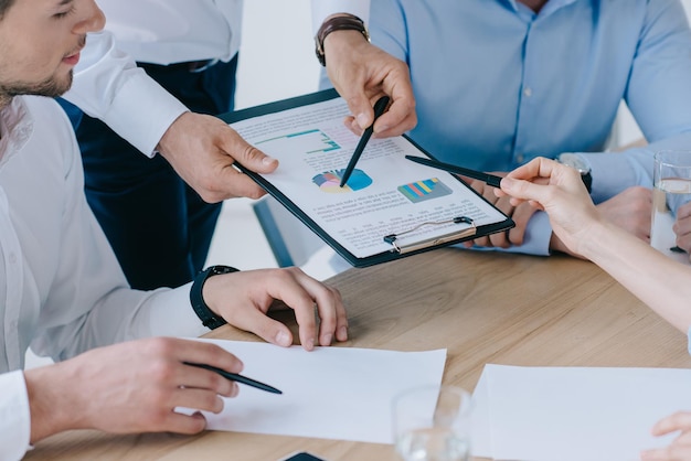 Partial view of business people working on business plan at workplace in office