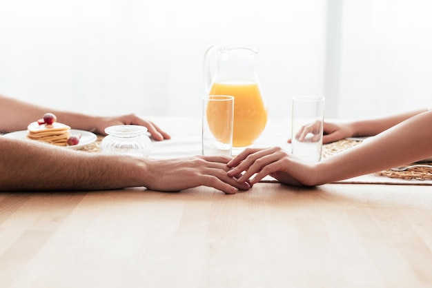 Partial view of couple touching hands during breakfast