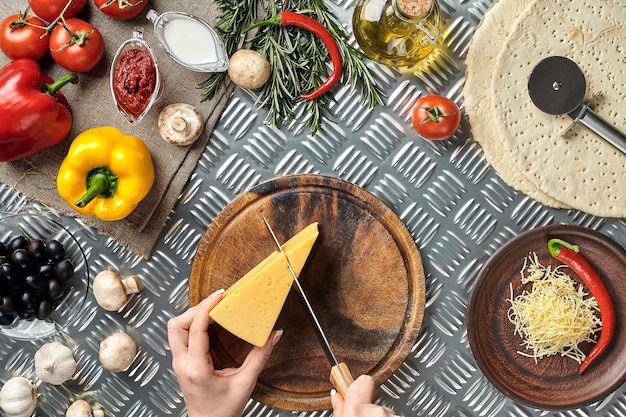 Partial view of woman cutting cheese while cooking homemade italian pizza