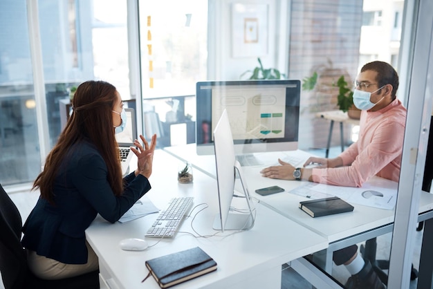 Partitions allow employees to work more safely in the time of COVID19 Shot of two businesspeople wearing face masks while working together in an office