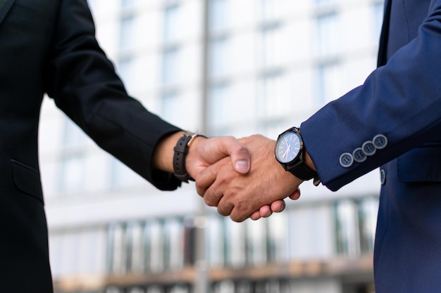 Partners greeting in business district. Business man and woman in office suits shaking hands