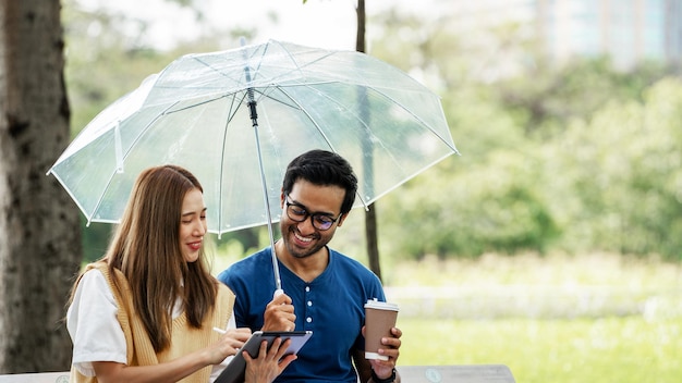 Partnership Student Friend holding Umbrella and working study with Partner support together at Park Business young Couple Partner Discuss at the outdoor Business Colleagues Outside Office A Couple