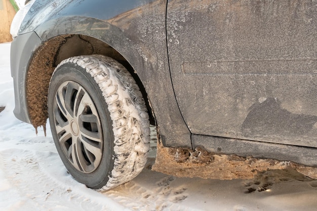 Parts of the car are covered with snow and ice after a snowfall Wheel closeup in dirt and antiicing reagents Big frosts and a lot of snow in the city Problems on winter slippery roads