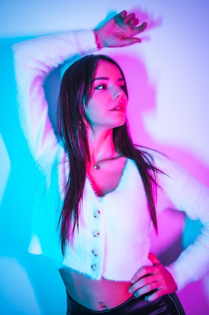 Party lifestyle in a nightclub with pink blue neon lights portrait of a young brunette Caucasian woman in a woolen sweater