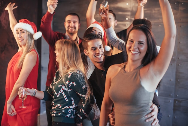 Party with friends. They love Christmas. Group of cheerful young people carrying sparklers and champagne flutes dancing in new year party and looking happy. Concepts about togetherness lifestyle