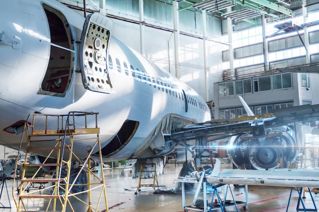 Passenger jet plane under maintenance in the hangar. Checking mechanical systems for flight operations. Close-up view the back of the aircraft with the door open