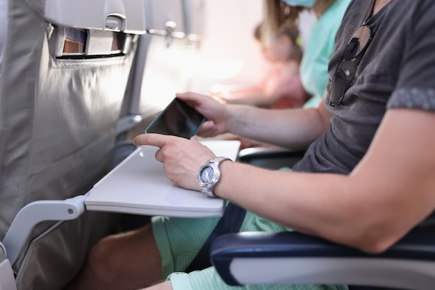 Passenger of plane sit still and hold phone in his hands.