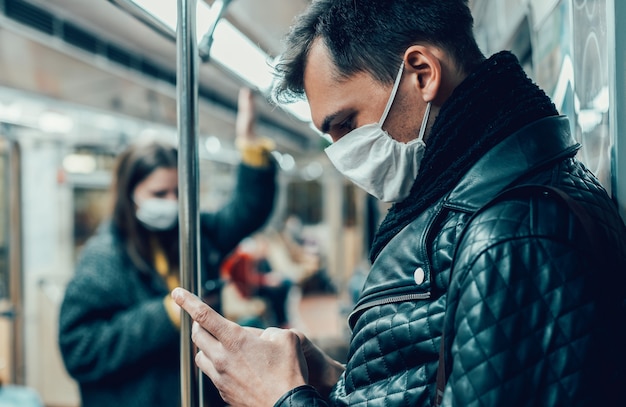 Passenger in a protective mask reading a message on his smartphone