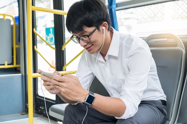 Passenger transport. people in the bus, listening music and play game while riding home.