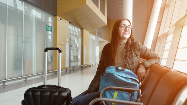 Passenger traveler woman in airport waiting for air travel and looking window