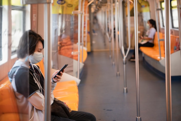 Passengers looking at mobile phones while on the electric train BTS in Bangkok Thailand