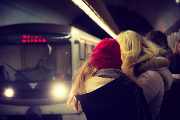 Photo passengers waiting for illuminated train to arrive at railroad station