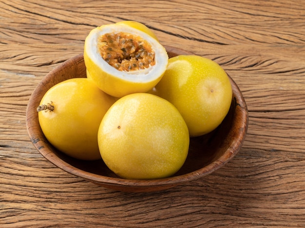 Passion fruits in a bowl with cut fruit over wooden table