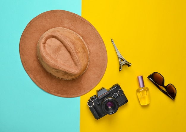 Passion for travel, wanderlust concept. Trip to France, Paris. Felt hat, film camera, sunglasses, perfume bottle, souvenir statue of Eiffel Tower layout on a colored paper background. Flat lay.