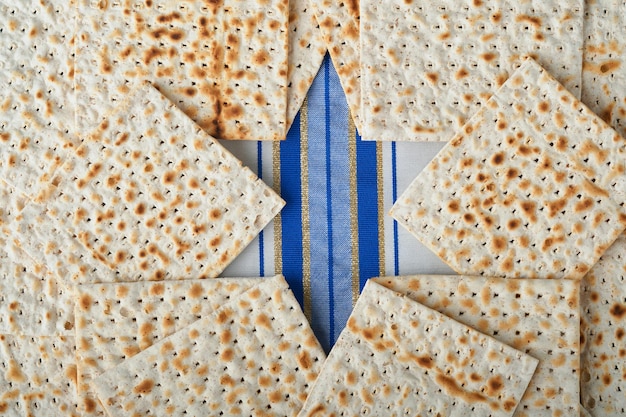 Passover celebration concept Blue Star of David made from matzah white and yellow roses kippah and walnut on bluebackground Traditional ritual Jewish Passover food Pesach Jewish holiday Mock up