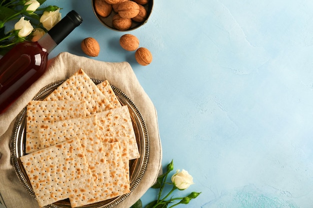 Passover celebration concept Matzah red kosher walnut and spring beautiful rose flowers Traditional ritual Jewish bread on light turquoise or blue background Passover food Pesach Jewish holiday