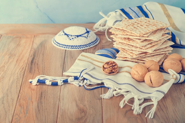 Passover celebration concept Matzah red kosher and walnut Traditional ritual Jewish bread matzah kippah and tallit on old wooden background Passover food Pesach Jewish holiday Toned image