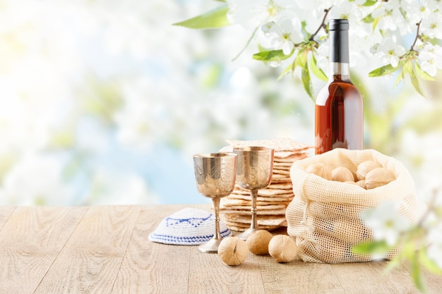 Passover celebration concept Matzah red kosher and walnut on wooden vintage table table in front of spring blossom tree garden and flowers landscape with sun rays with copy space Mock up