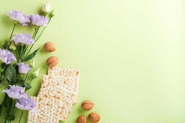 Passover celebration concept Matzah red kosher wine walnut and spring beautiful rose flowers Traditional ritual Jewish bread on light green background Passover food Pesach Jewish holiday