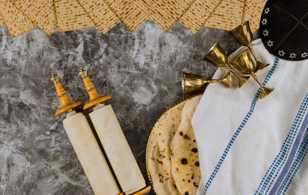 Photo passover day traditional celebration with four cup for wine and kosher matzah unleavened bread on torah scroll of jewish holiday pesach