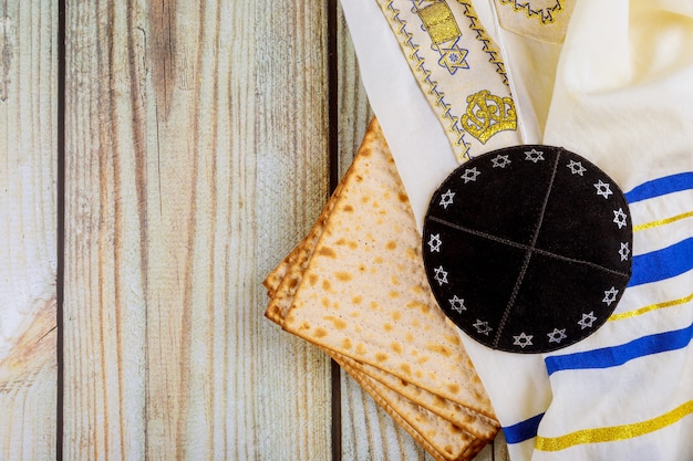 Photo passover matzoh jewish holiday bread kippah and tallit on wooden table.