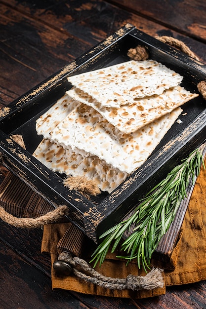 Passover matzos of celebration with matzo unleavened bread in a wooden tray with herbs Wooden background Top view