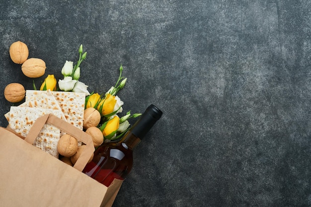 Passover Pesah celebration concept Matzah kosher red wine walnut and white and yellow roses Traditional ritual Jewish bread on sand color old tile wall background Pesach Jewish holiday Top view