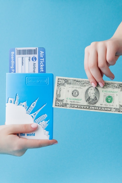 Passport, dollars and air ticket in woman hand on a blue