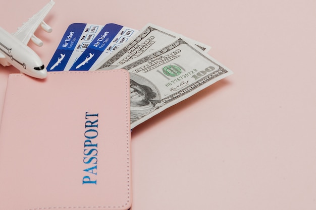 Passport, dollars, plane and air ticket on a pink background. Travel concept, copy space