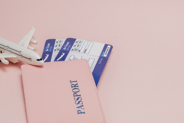 Passport, dollars, plane and air ticket on a pink background. Travel concept, copy space