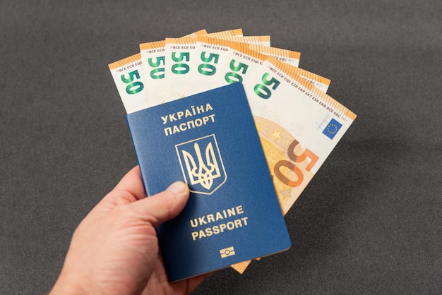 Passport of Ukraine and euro banknotes in hand Monetary compensation cash payments assistance to Ukrainians abroad Corruption and bribery in Ukraine