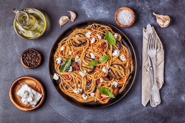 Pasta alla Norma. traditional Italian food with eggplant, tomato, cheese and basil, top view.