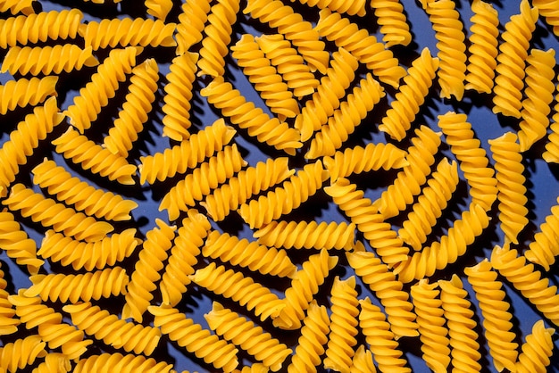 Pasta dry spiral italian yellow on blue background pattern Flatlay and top view