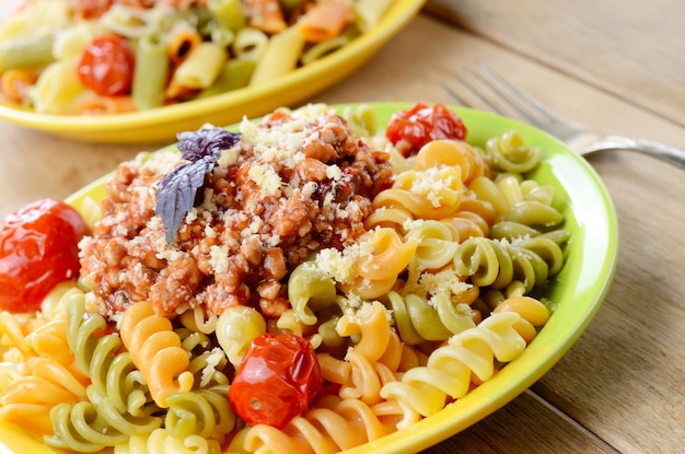 Pasta fusilli with bolognese tomato beef sauce and dried tomatoes on the kitchen table