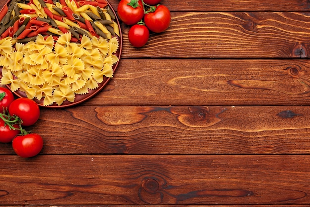 Pasta and ingredients on wooden background with copy space. Top view.