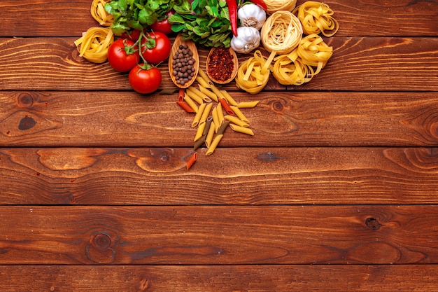 Pasta and ingredients on wooden table with copy space background. Top view.