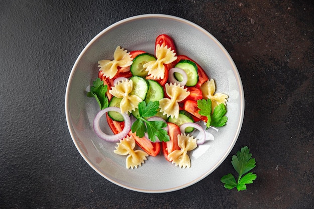 Pasta salad farfalle tomato cucumber onion healthy meal diet snack on the table