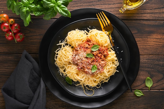 Pasta spaghetti Bolognese Tasty appetizing italian spaghetti with bolognese sauce tomato sauce cheese parmesan and basil on white plate on old wooden rustic table background Top view