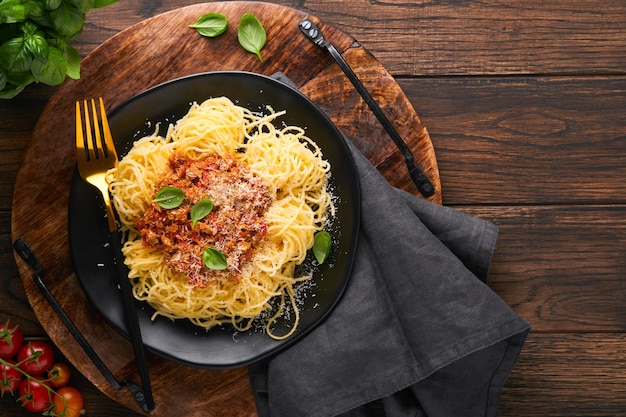 Pasta spaghetti Bolognese Tasty appetizing italian spaghetti with bolognese sauce tomato sauce cheese parmesan and basil on white plate on old wooden rustic table background Top view