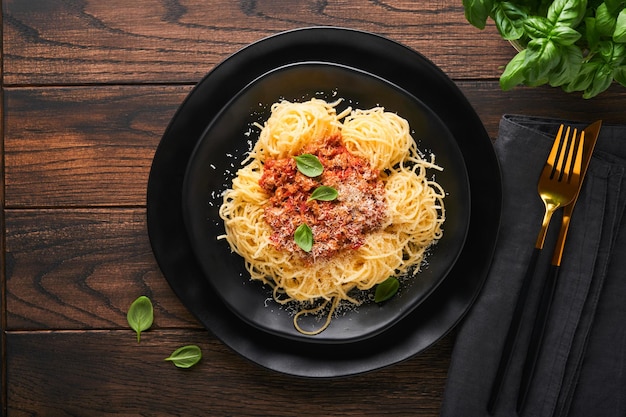 Pasta spaghetti Bolognese Tasty appetizing italian spaghetti with bolognese sauce tomato sauce cheese parmesan and basil on white plate on old wooden rustic table background Top view