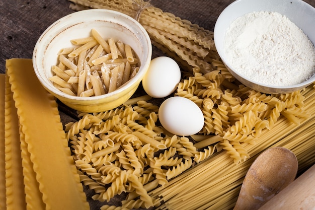 Pasta spaghetti with flour, egg on old wooden background