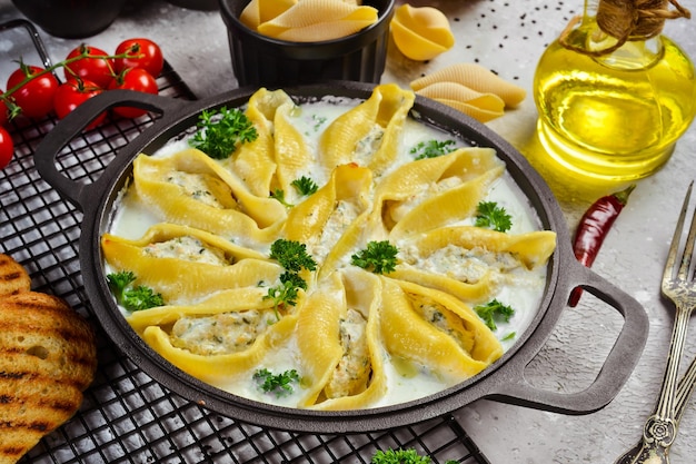 Pasta stuffed with meat cream sauce and parmesan In a frying pan Traditional Italian lunch On a stone background Recipe