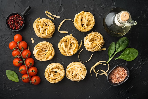 Pasta tagliatelle with ingredients set, on black stone table, top view flat lay