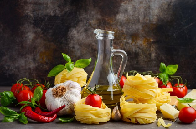 Pasta, vegetables, herbs and spices for Italian food on the wooden background.