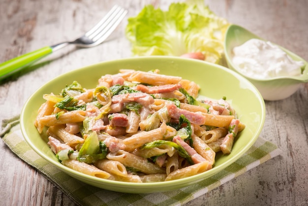 Pasta with bacon lettuce and cream sauce selective focus