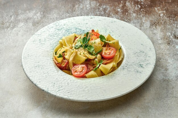 Pasta with bacon and tomatoes in a plate. Close-up, selective focus.