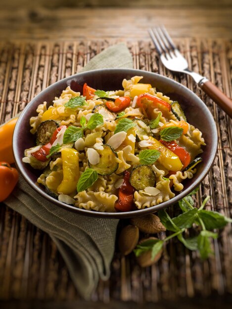 Pasta with capsicum zucchinis and sliced almond selective focus