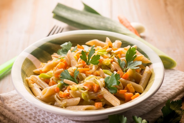 Pasta with carrot leek and pine nuts selective focus